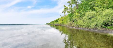 A calm river with clear water reflecting the sky and surrounding greenery.