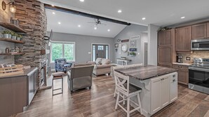 A spacious kitchen with a central island, wooden cabinets, and a stone accent wall. - Lakeside Retreat With Hot Tub & Game Room 3 Bedroom Home (Elkhart)