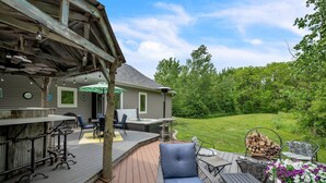 A deck with outdoor furniture, a hot tub, and a view of a grassy yard. - Lakeside Retreat With Hot Tub & Game Room 3 Bedroom Home (Elkhart)