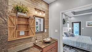 A bathroom with a wooden vanity, a large mirror, and a sink with a vessel basin. - Lakeside Retreat With Hot Tub & Game Room 3 Bedroom Home (Elkhart)