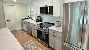 Une cuisine moderne avec des meubles blancs, des appareils en acier inoxydable et un tapis à motifs.