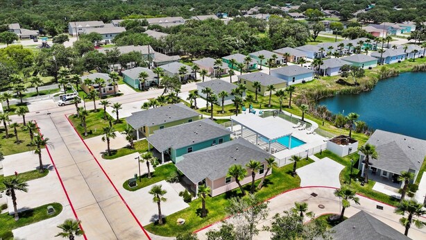 A residential area with houses, a swimming pool, and a lake. - Nauta Mirage 2 Bedroom Home (Rockport)