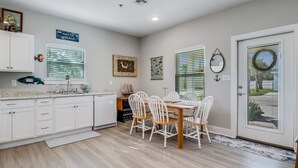 A kitchen with white cabinets, a dining table with white chairs, and a door with a glass panel. - Nauta Mirage 2 Bedroom Home (Rockport)
