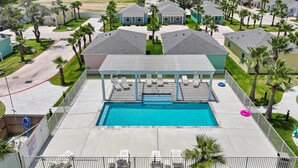 A residential area with a swimming pool, houses, and palm trees. - Nauta Mirage 2 Bedroom Home (Rockport)