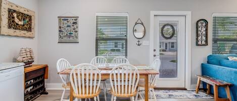 A dining area with a wooden table and white chairs, a small ship model, and a wine rack.