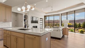 Une cuisine moderne dotée d’un grand îlot central, de meubles en bois et offrant une vue sur le désert grâce à de grandes fenêtres.