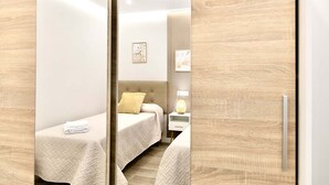 A bedroom with two beds, a bedside table with a lamp, and a wall-mounted artwork.