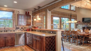 A spacious kitchen with wooden cabinets, a large island, and a dining area with a table and chairs. - 5BR Ski-In/Ski-Out Cabin, Hot Tub, Fireplace & Mountain Views – Big Sky, MT (Big Sky)