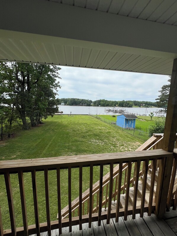 A wooden deck with a view of a lake and dock.