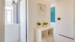 Un pasillo con una consola blanca, un letrero enmarcado que dice 'LOVE' y una puerta con un detalle en pared azul.