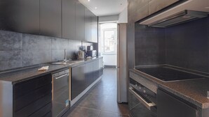 Una cocina moderna con armarios oscuros, lavavajillas integrado y una campana extractora de acero inoxidable.
