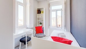 Habitación pequeña con escritorio, silla y cama con toallas.