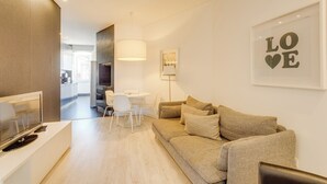 Una sala de estar moderna con un sofá, un televisor y un comedor con sillas y una mesa.