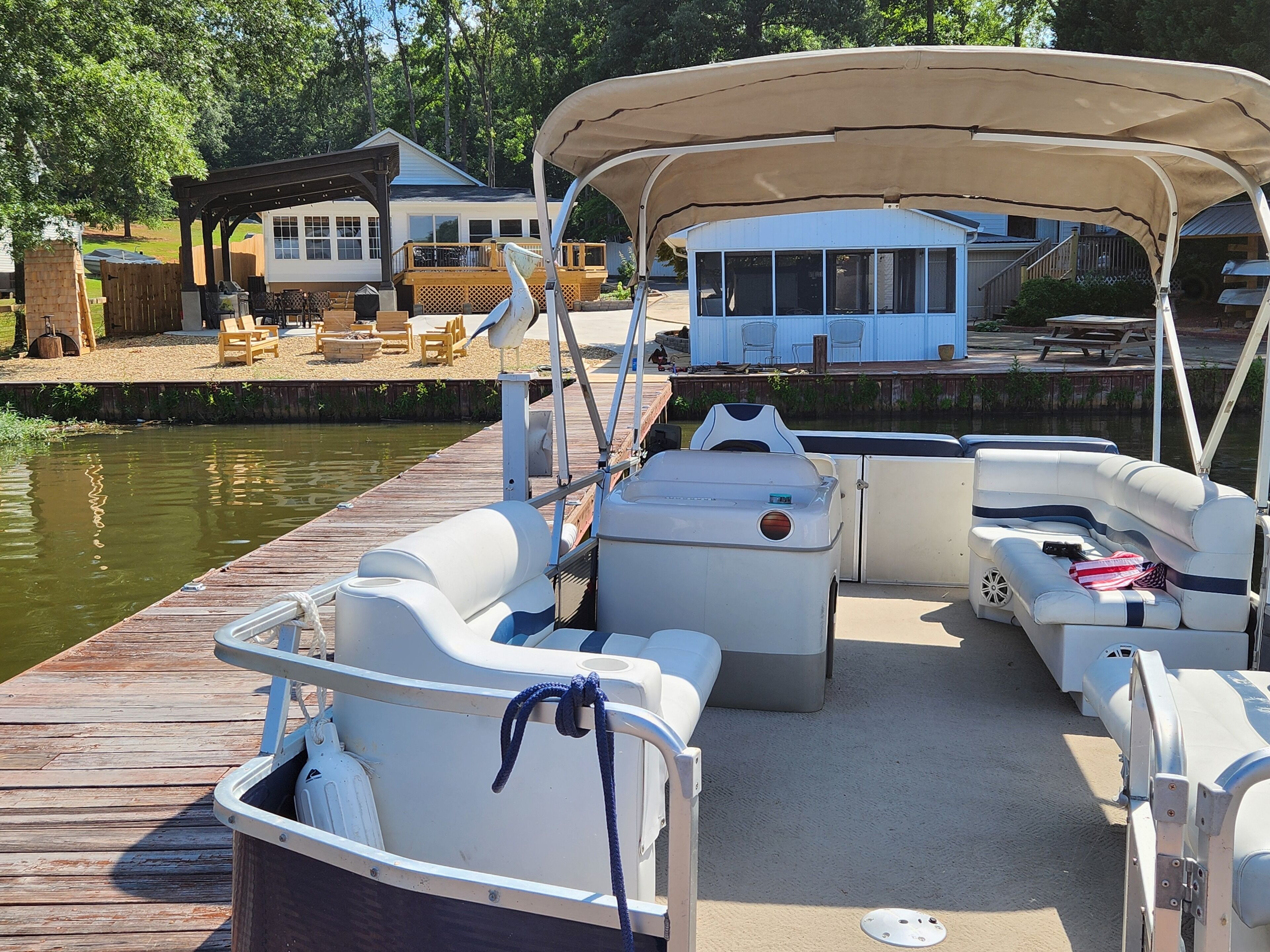 A boat docked at a pier with a covered seating area, a small cabin, and a lounge chair.