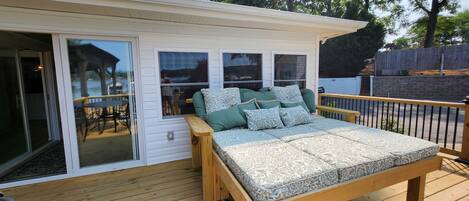 Un dormitorio con una cama de madera, un ventanal corredero y vistas a un patio con mobiliario exterior.