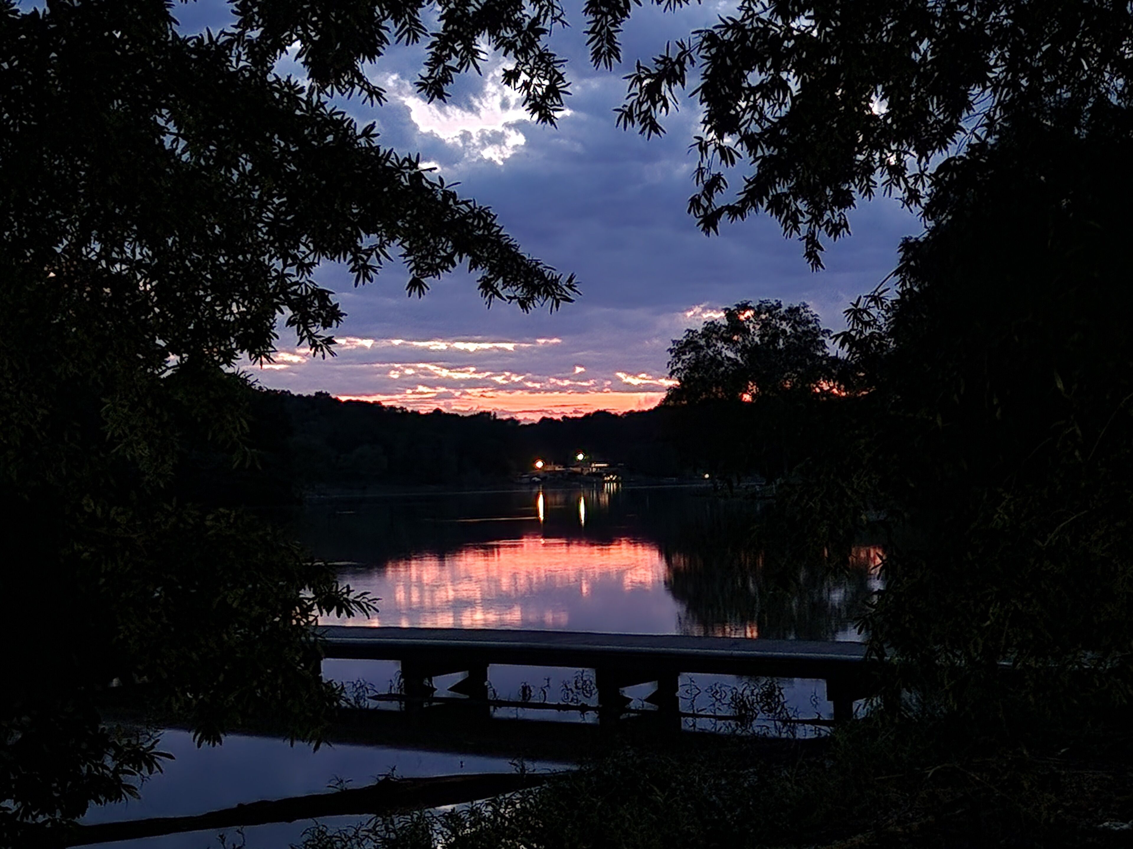 Una vista tranquila de un lago, con un puente y árboles enmarcando la escena.