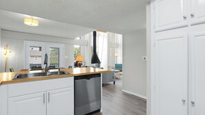 A modern kitchen with white cabinetry, a dishwasher, and a wooden countertop.