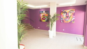 A modern interior with purple walls, two large abstract paintings, a staircase, and potted plants. - Las Gacelas Playa del Ingles (San Bartolome de Tirajana)