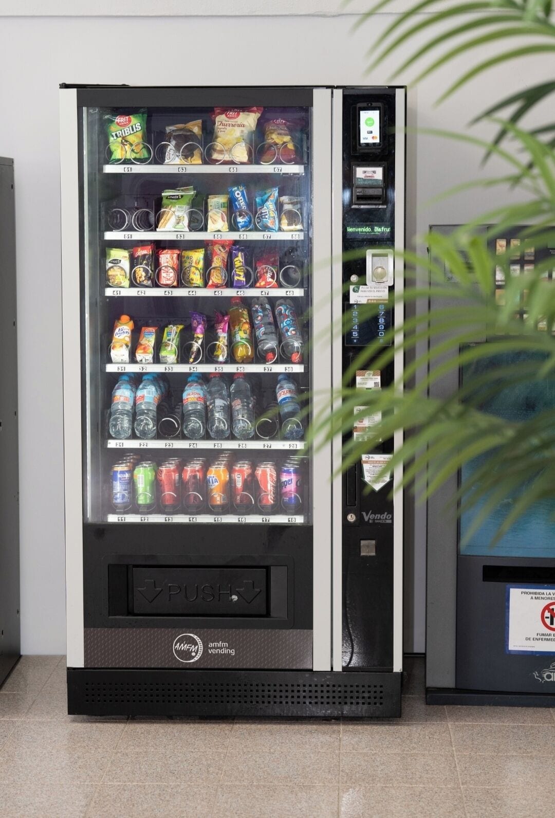 A vending machine with various snacks, drinks, and a payment interface.