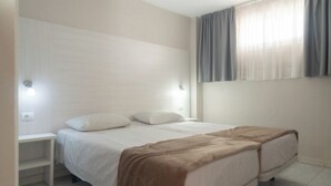A bedroom with a bed, nightstands, and a window with curtains. - Las Gacelas Playa del Ingles (San Bartolome de Tirajana)