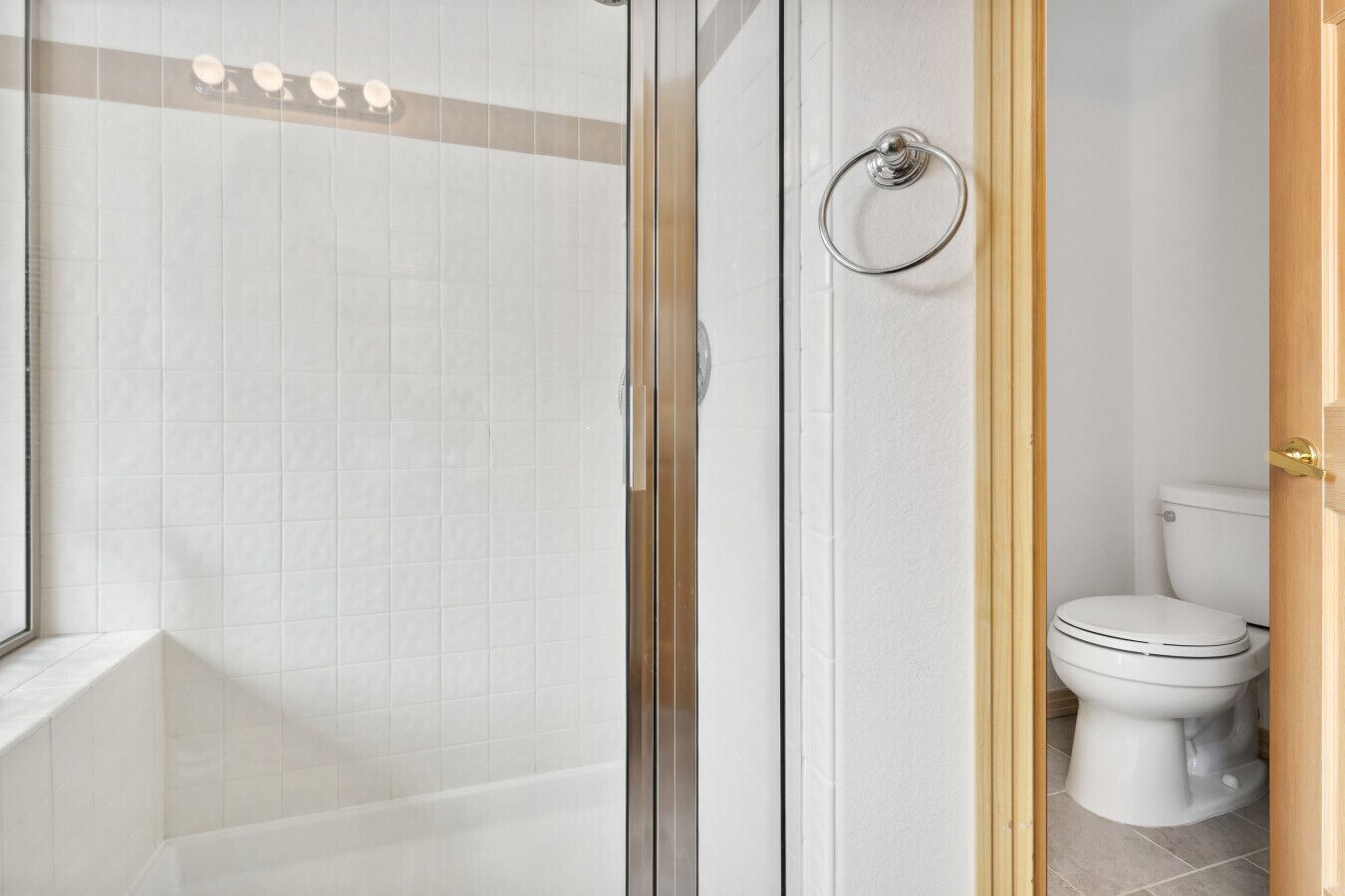 A modern bathroom with a glass shower enclosure, a toilet, and a towel ring.