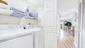 A laundry area with two washing machines, a drying rack, and a basket. - Treasure Island Beach Front Spectacular Sunsets South Beach 405 (Treasure Island)