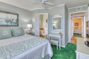 A bedroom with a bed, a vanity with a mirror, a ceiling fan, and a painting on the wall. - Two Bedroom Condo with a Shared Swimming Pool on the channel front. (Garden City Beach)