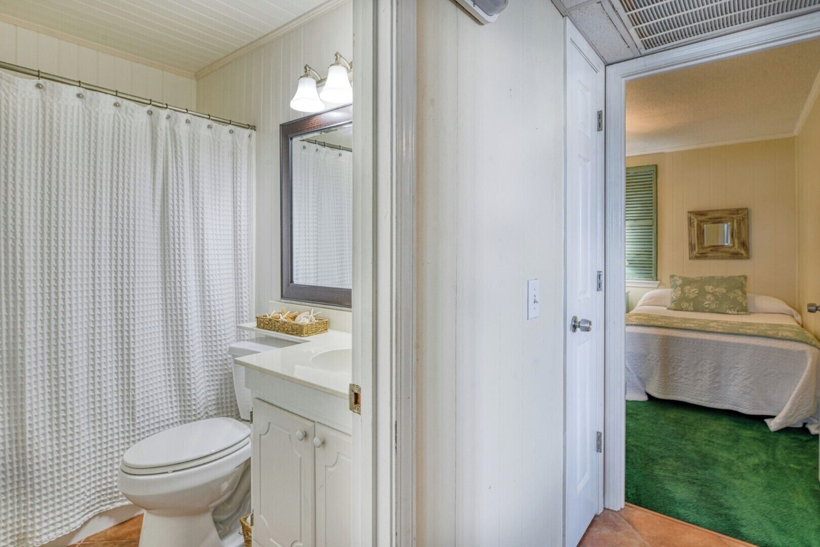 A bathroom with a toilet, sink, and shower curtain.
