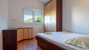 Une chambre à coucher avec un lit, une armoire en bois et une fenêtre avec des stores.