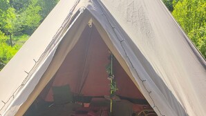 Een tent met een bed, een tafeltje en een stoel van binnen.