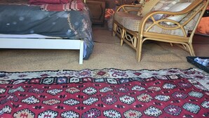 Een gezellig ingericht tentinterieur met een bed, een rieten stoel, een kleine tafel met een plant en een kamerkleed.
