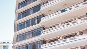 Ein mehrstöckiges Hotel mit Balkonen, Klimaanlagen und einem Schwimmbad.