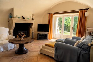 A living room with a fireplace, a television, a sofa, and a dining table.