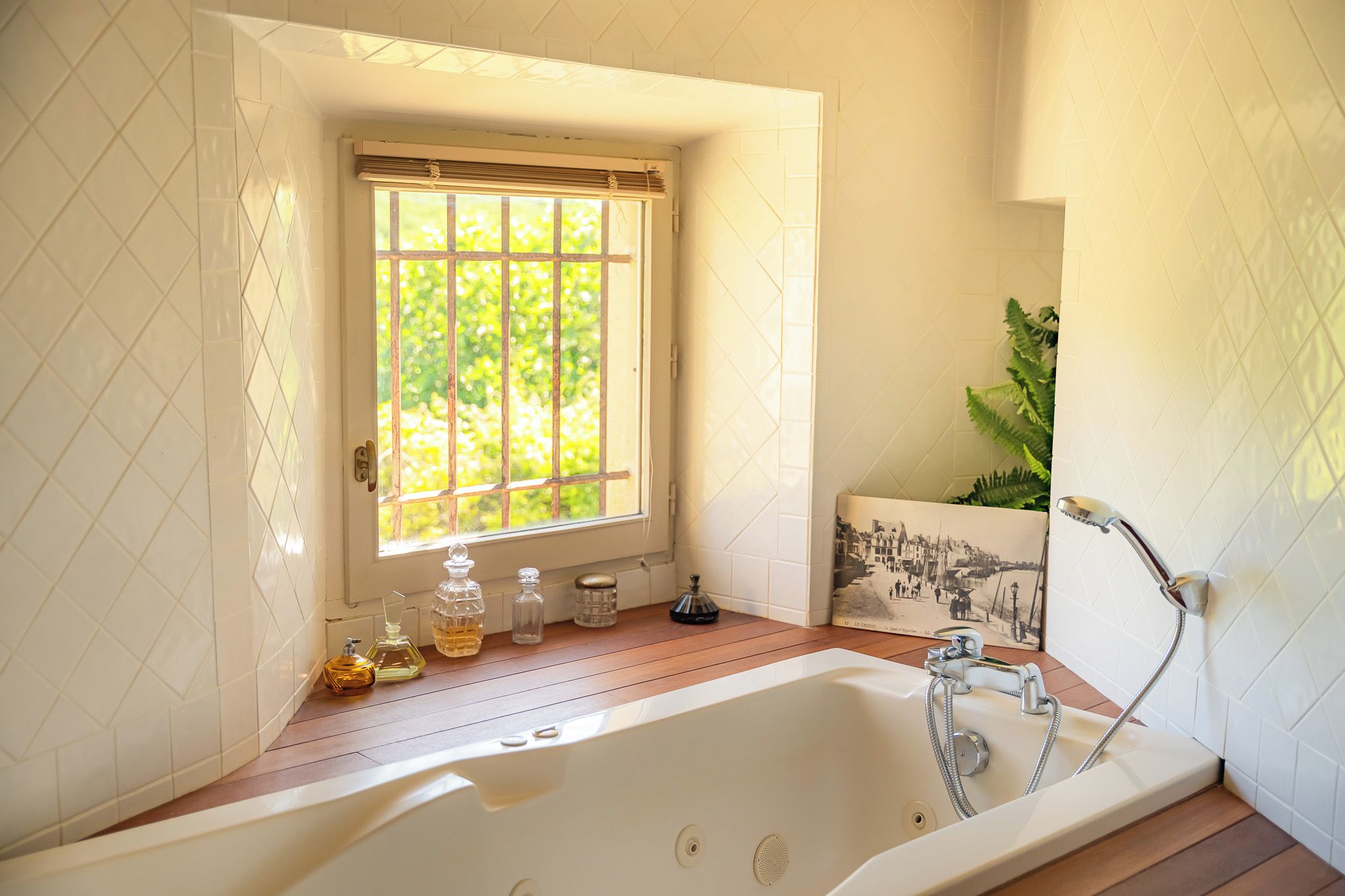 A bathroom with a bathtub, a window with bars, and a plant.