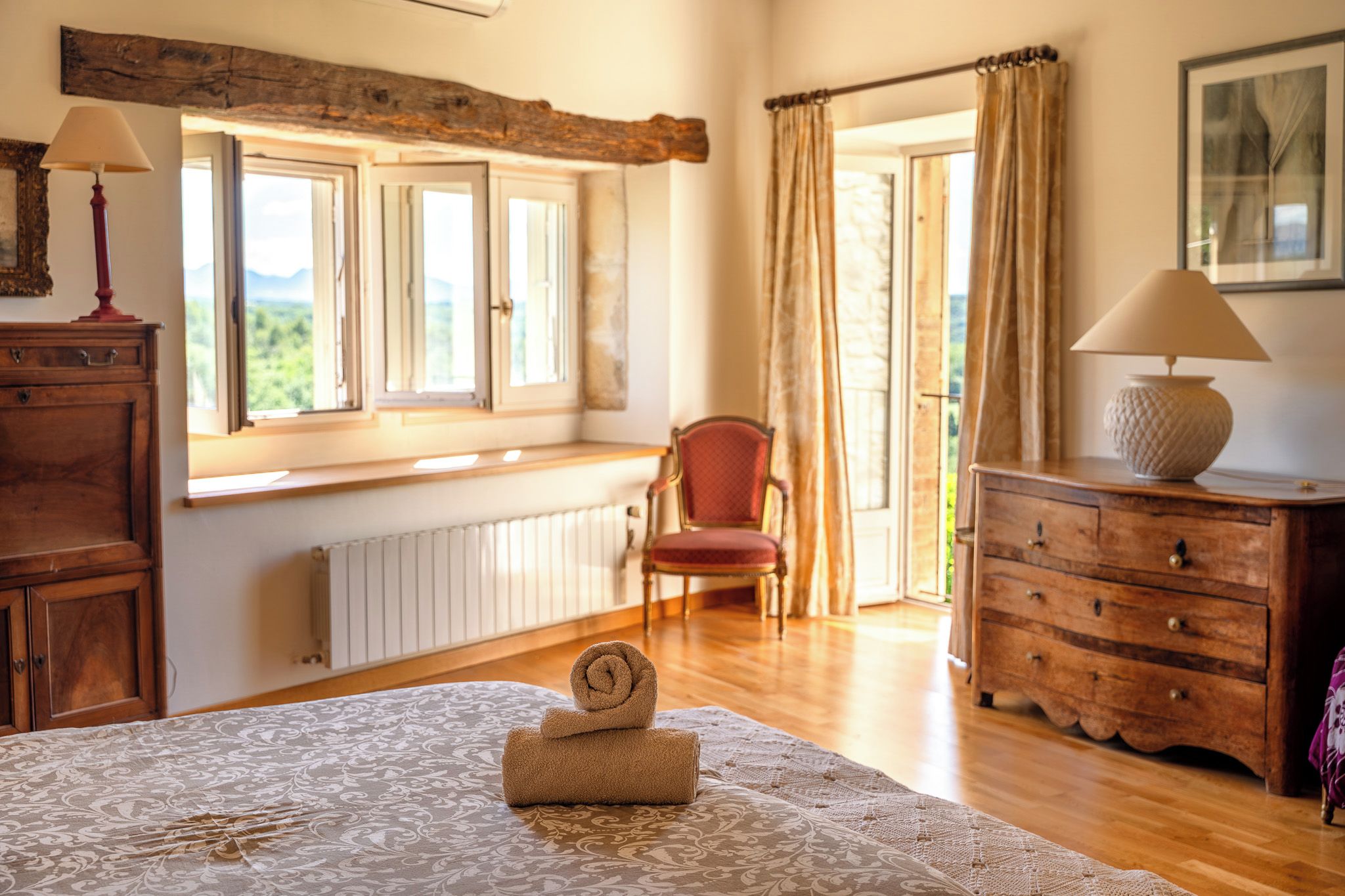Een kamer met een bed, een stoel, een kaptafel en een raam met gordijnen.
