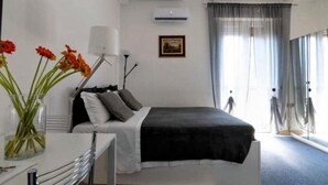 A bedroom with a bed, a bedside table, a lamp, a picture on the wall, and a window with curtains. - Short Rent Milan Porta Vittoria. Studio apartment with balcony (Milano)