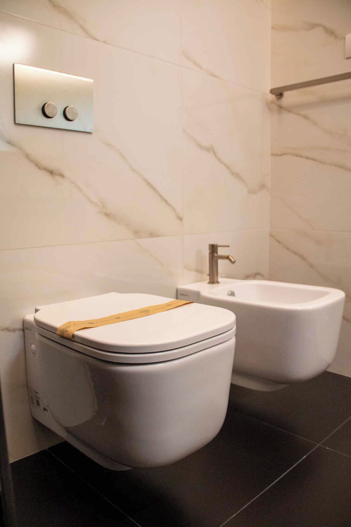 Ein modernes Badezimmer mit Toilette, Bidet und einer Wandleuchte.