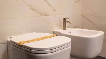 Ein modernes Badezimmer mit Toilette, Bidet und einer Wandleuchte.