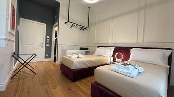 Habitación de hotel con dos camas, un tocador con espejo y una pequeña zona de estar.