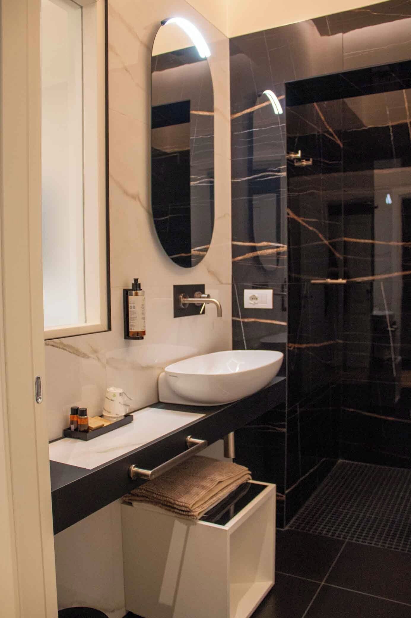A modern bathroom with a white sink, a large mirror, and a glass shower enclosure.