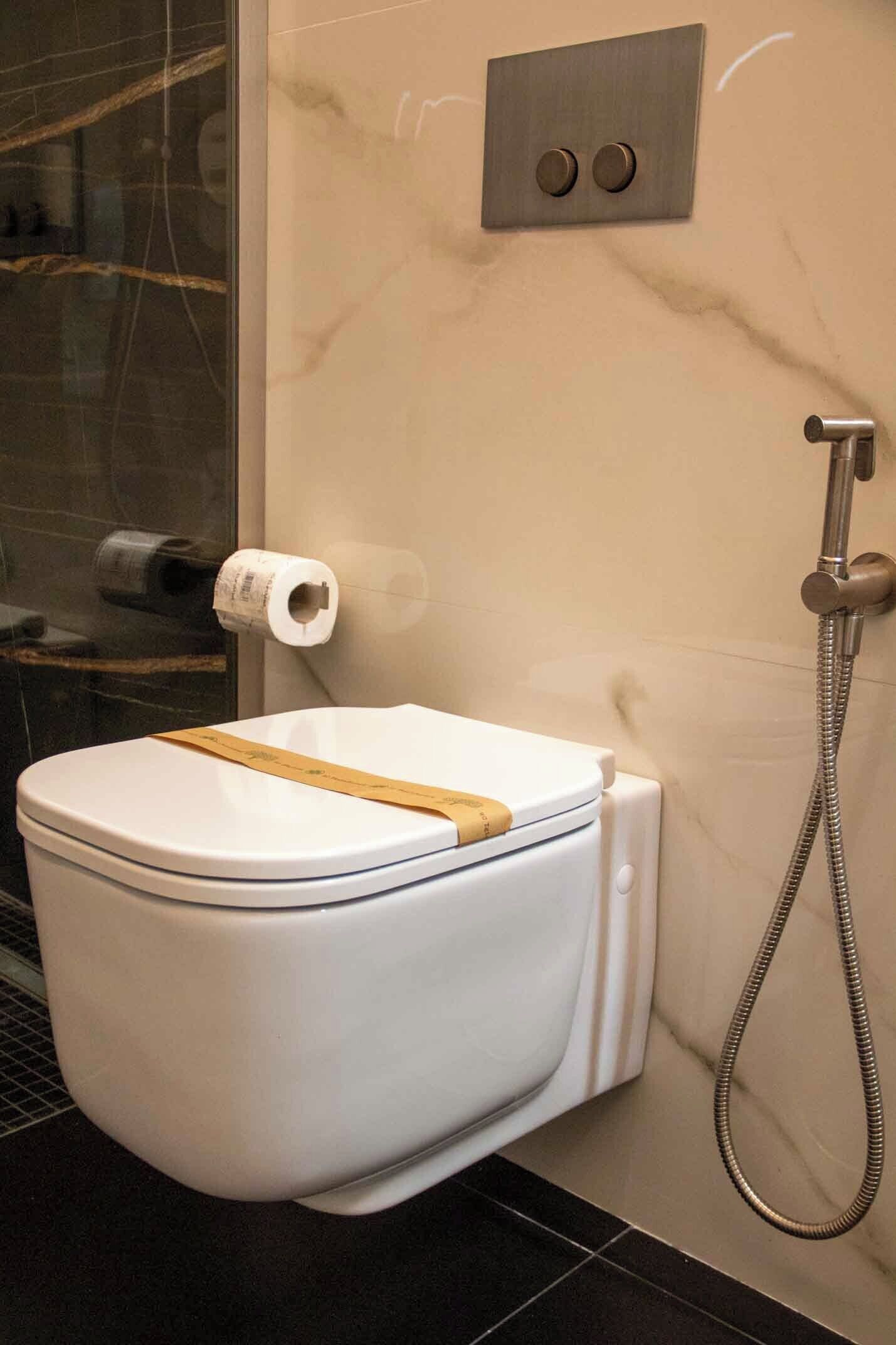 A modern bathroom with a white toilet, a shower, and a marble wall.