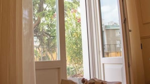 Une chambre avec un lit, une fenêtre donnant sur les arbres et un balcon, ainsi qu’un porte-serviettes avec des serviettes.
