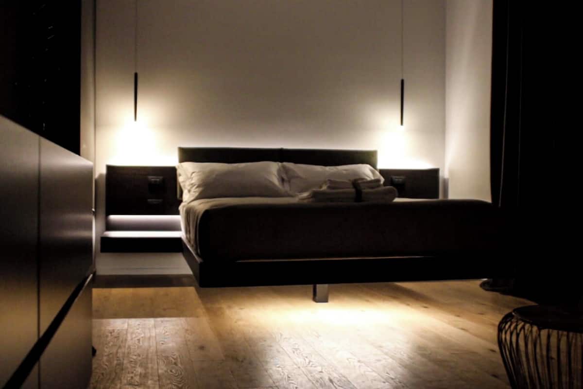 A modern bedroom with a large bed, two bedside tables, and a wooden floor.