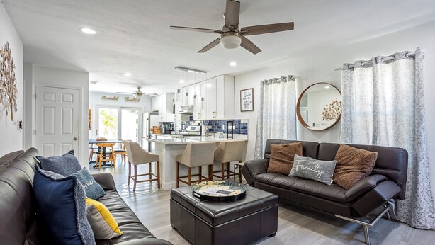 A modern living room with a brown leather sofa, a coffee table, and a ceiling fan.