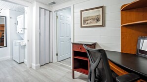 A room with a desk, chair, and a framed picture on the wall.