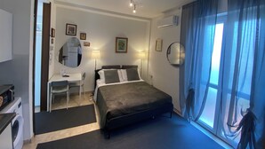 Habitación de hotel con cama, escritorio, silla y lavadora.