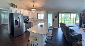 A modern kitchen with a central island, bar stools, a built-in oven, and a refrigerator. - Charming 3-bedroom family friendly Lakehouse in lovely Sebring  (Sebring)