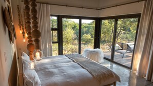 A bedroom with a large bed, a view of the outdoors through a sliding glass door, and a wooden deck outside. - Villa Aloe Vera in Hoedspruit (Hoedspruit)