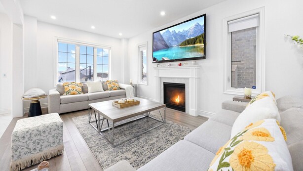A modern living room with a fireplace, a large flat-screen TV, and a cozy seating area. - Caledon Escape I 7BR Home with BBQ & Backyard (Caledon)