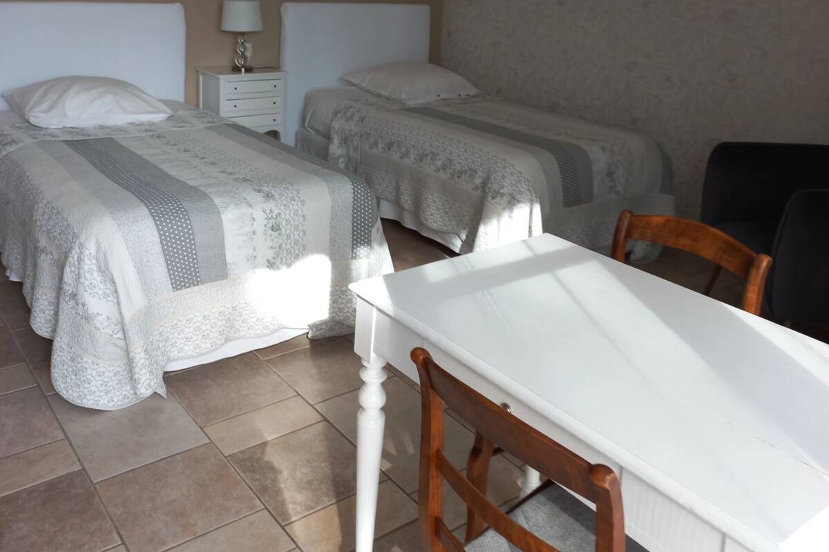 Une chambre d’hôtel avec deux lits, une petite table et une chaise.